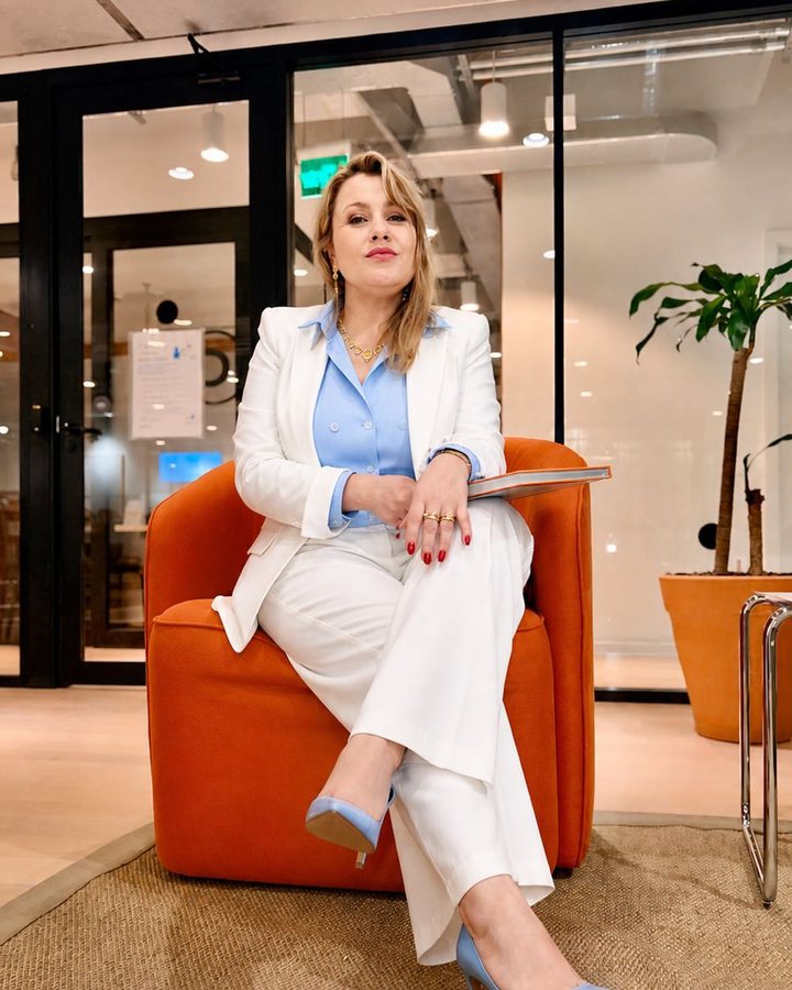 Euriale Voidela em ambiente corporativo, sentada em poltrona laranja